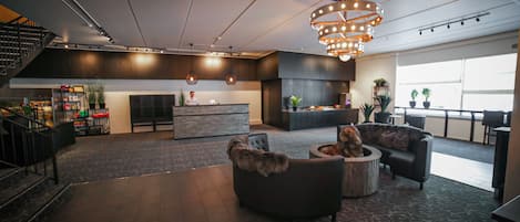 En rummelig lobby med et moderne design, med et centralt siddeområde, en trappe og et barområde.