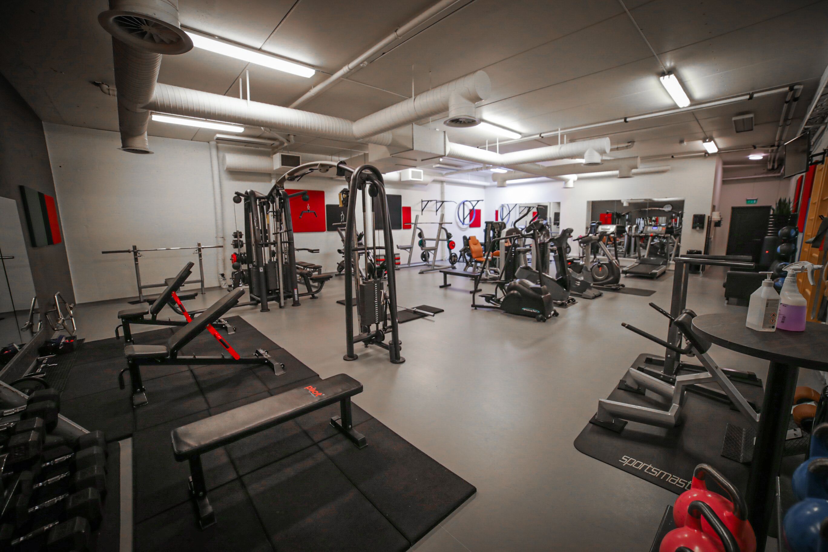 A gym with various exercise equipment, including benches, treadmills, and weight machines.