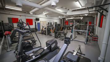 Un gimnasio con diferentes equipos de ejercicio, incluyendo cintas de correr, máquinas de pesas y pesas libres.