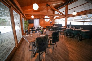 A wooden interior with tables and chairs, a television, and large windows. - Vesterland Feriepark Cabins & Apartments (Sogndal)