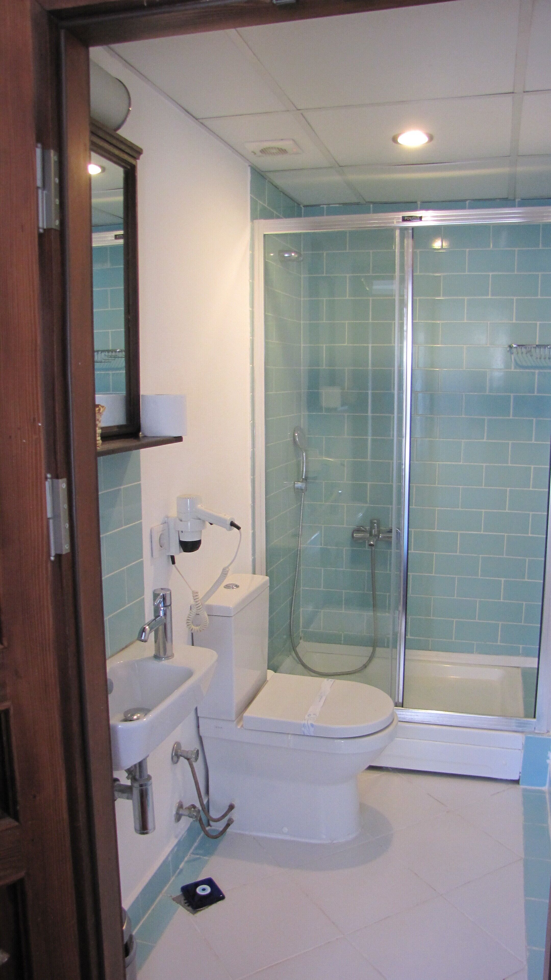 A bathroom with a glass-enclosed shower, a toilet, and a sink.