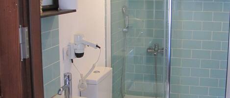A bathroom with a glass-enclosed shower, a toilet, and a sink.