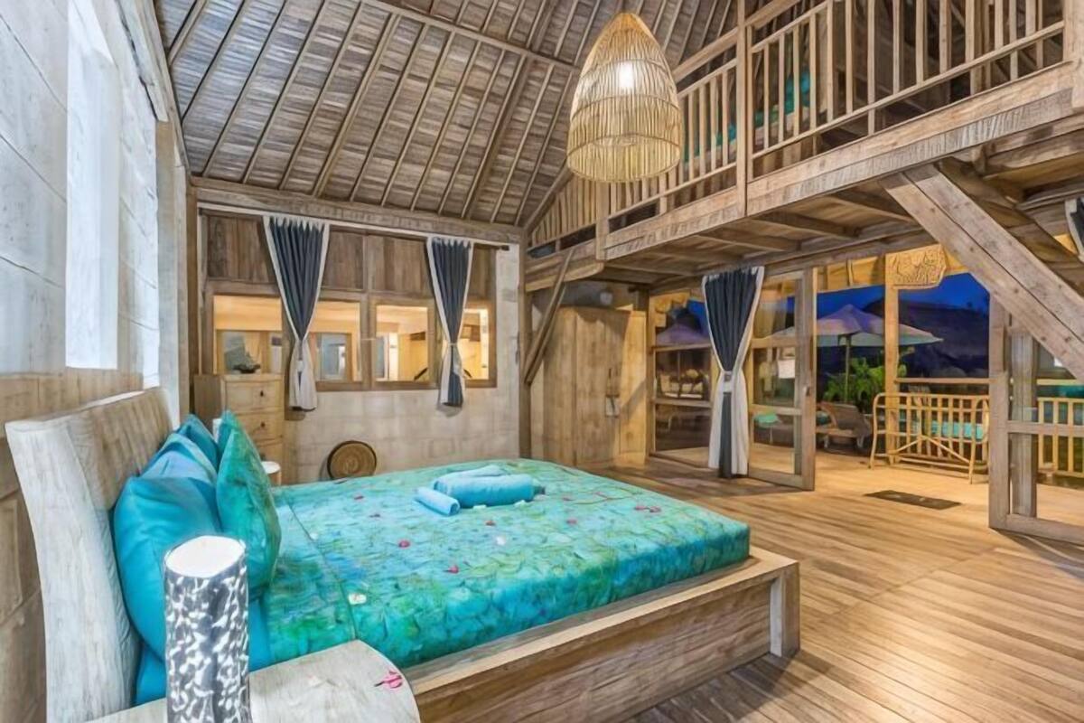 Un interior de madera con una cama, una lámpara colgante y un balcón.
