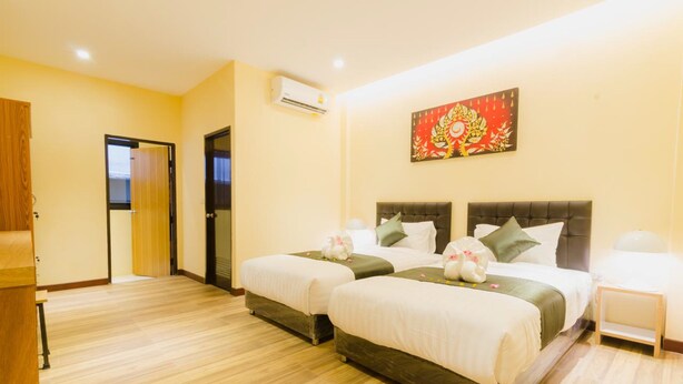 A hotel room with two beds, a wooden floor, an air conditioning unit, and a decorative wall piece. - My Living Place Nathon (Koh Samui)