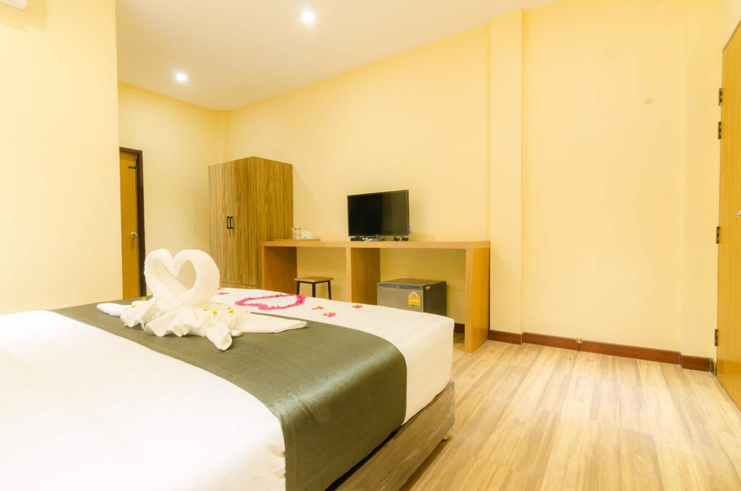 Habitación de hotel con cama, televisor sobre un mueble, armario y escritorio con silla.