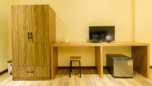 A room with a wooden wardrobe, a small table, a television, and a refrigerator. - My Living Place Nathon (Koh Samui)