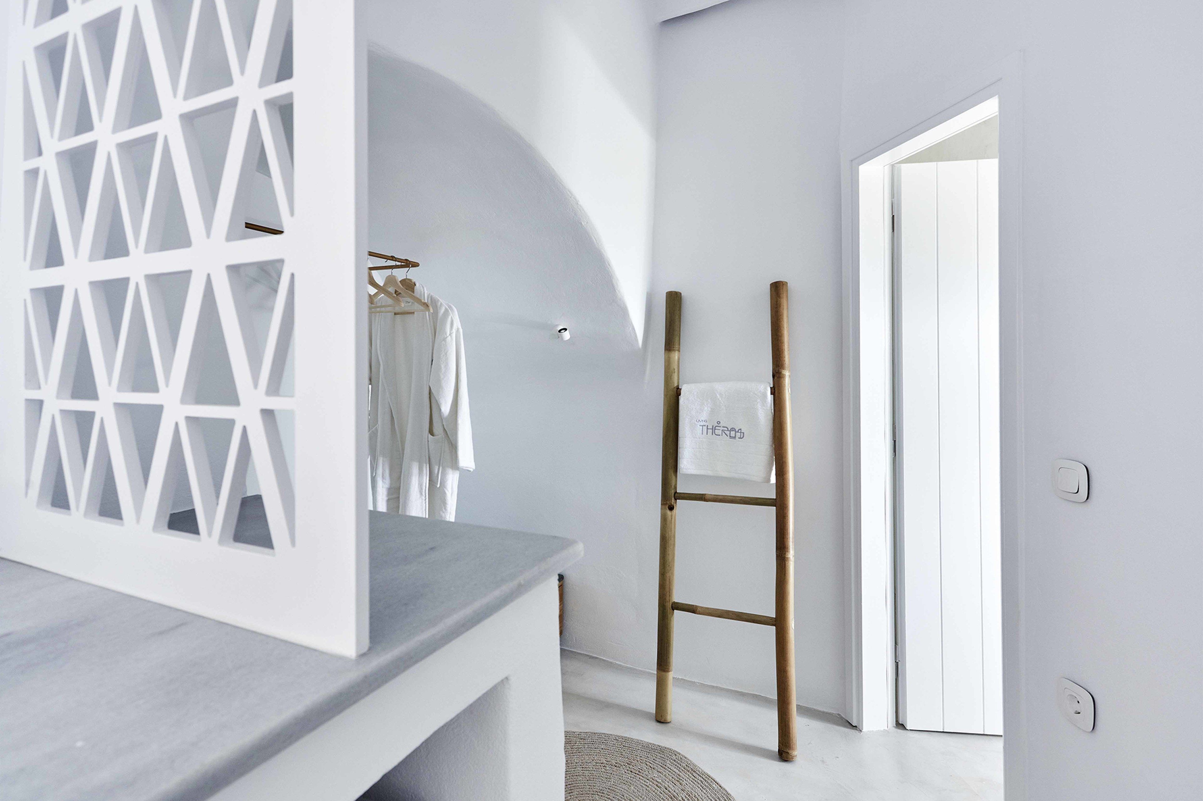 Une salle de bain moderne avec un meuble-lavabo blanc, un porte-serviettes avec une serviette et un escabeau en bambou.