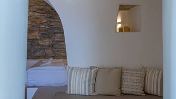 Una habitación acogedora con pared de piedra, un banco con cojines, un espejo pequeño e iluminación de pared.