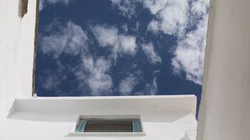 Un edificio blanco con una ventana pequeña y un cielo azul despejado con nubes.