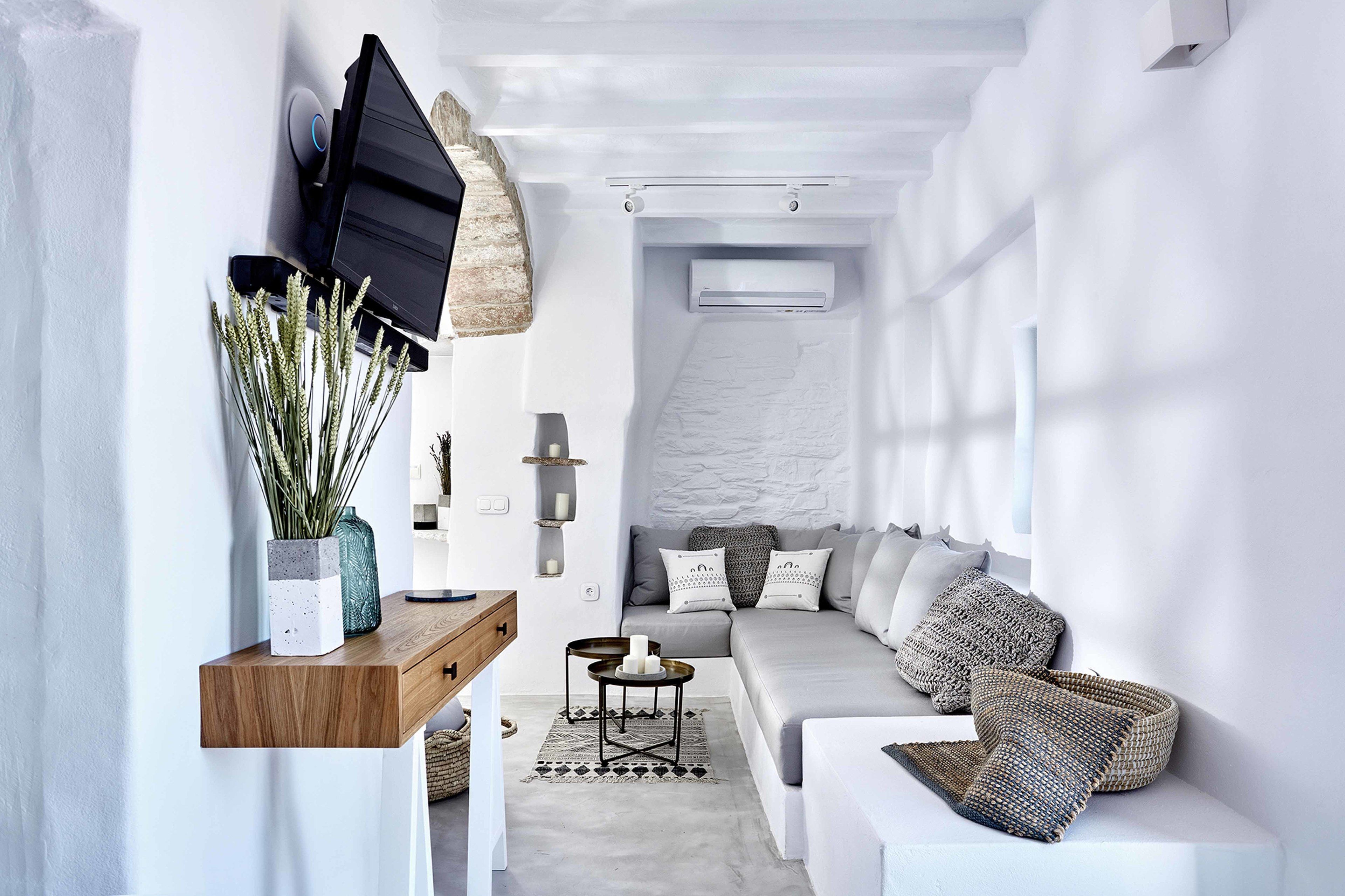 A modern living room with a white sofa, a wooden side table, and a mounted TV.