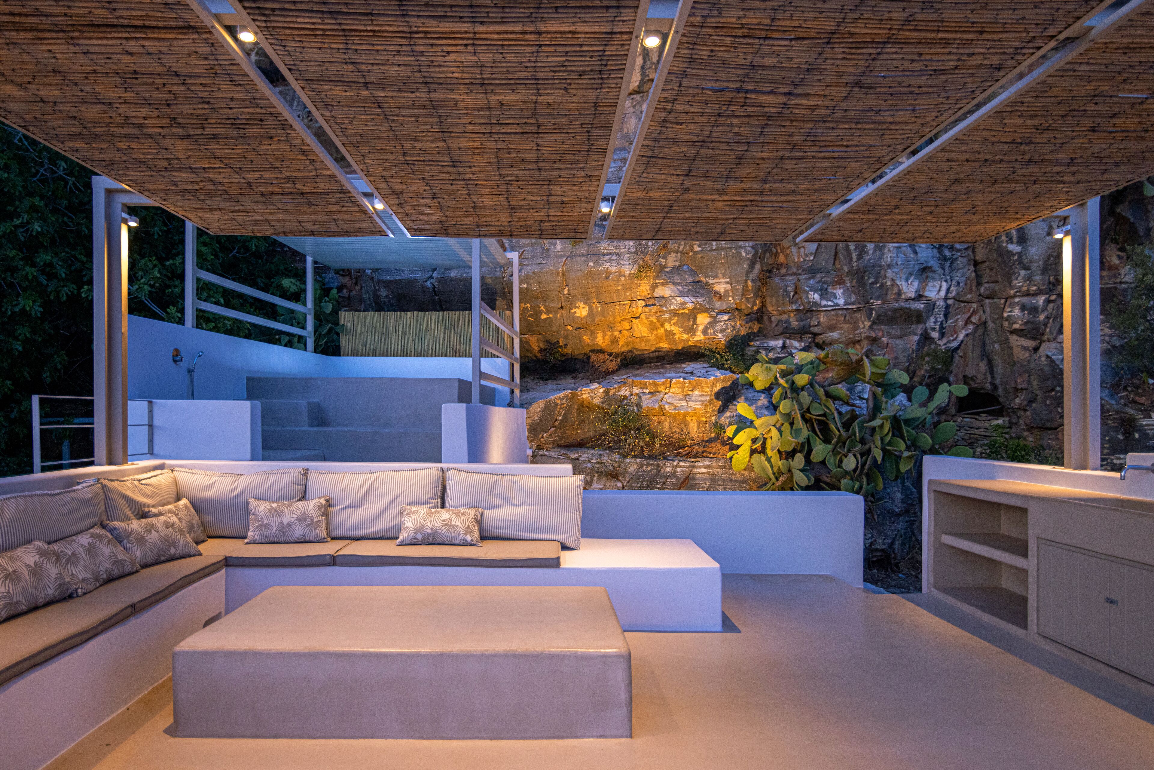 A modern interior with a large seating area, a rock wall, and a staircase leading to an upper level.