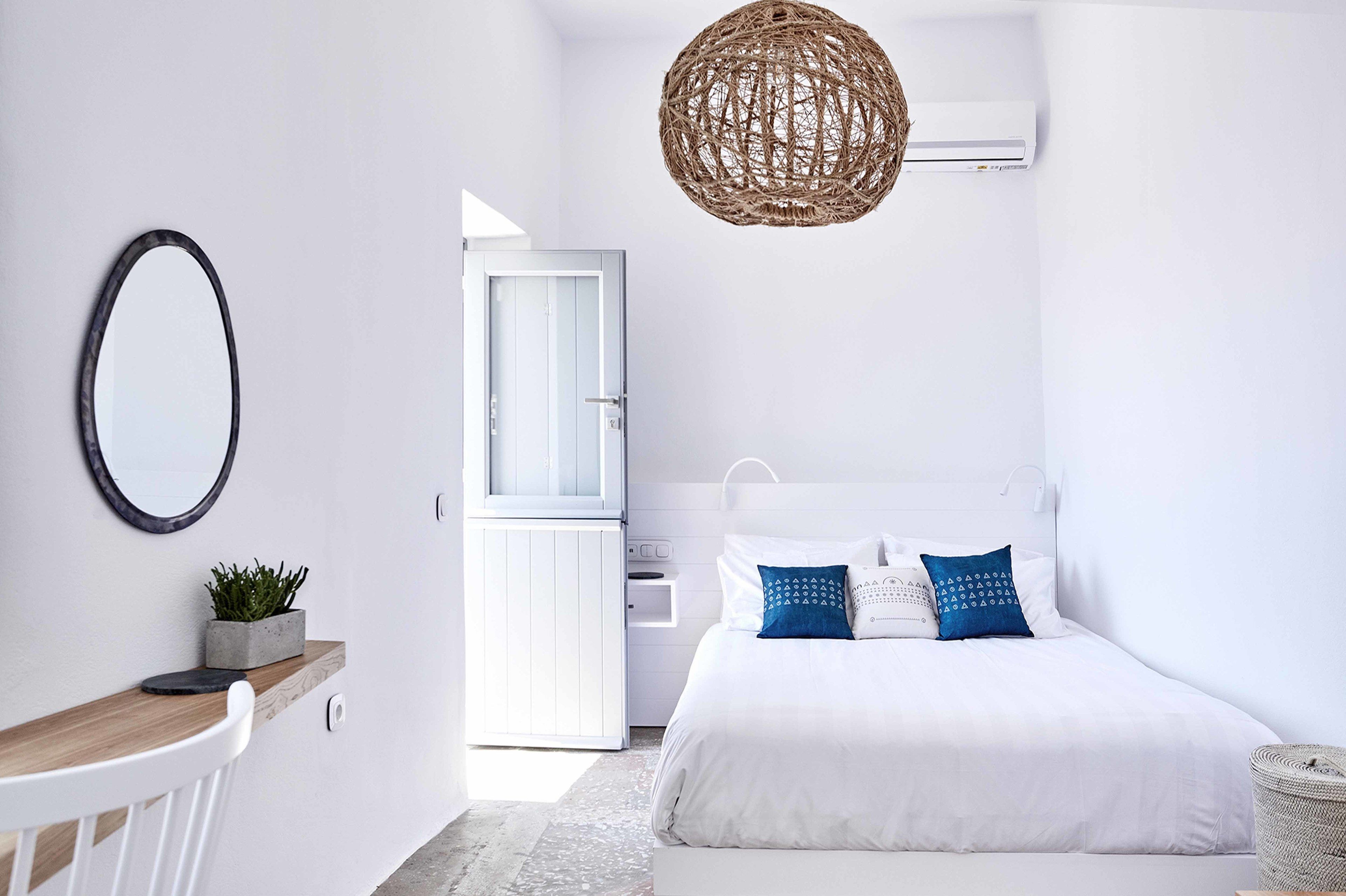 Un dormitorio minimalista con cama, mesita de noche y lámpara colgante.
