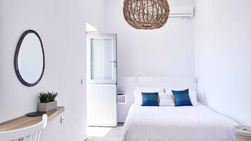 Un dormitorio minimalista con cama, mesita de noche y lámpara colgante.