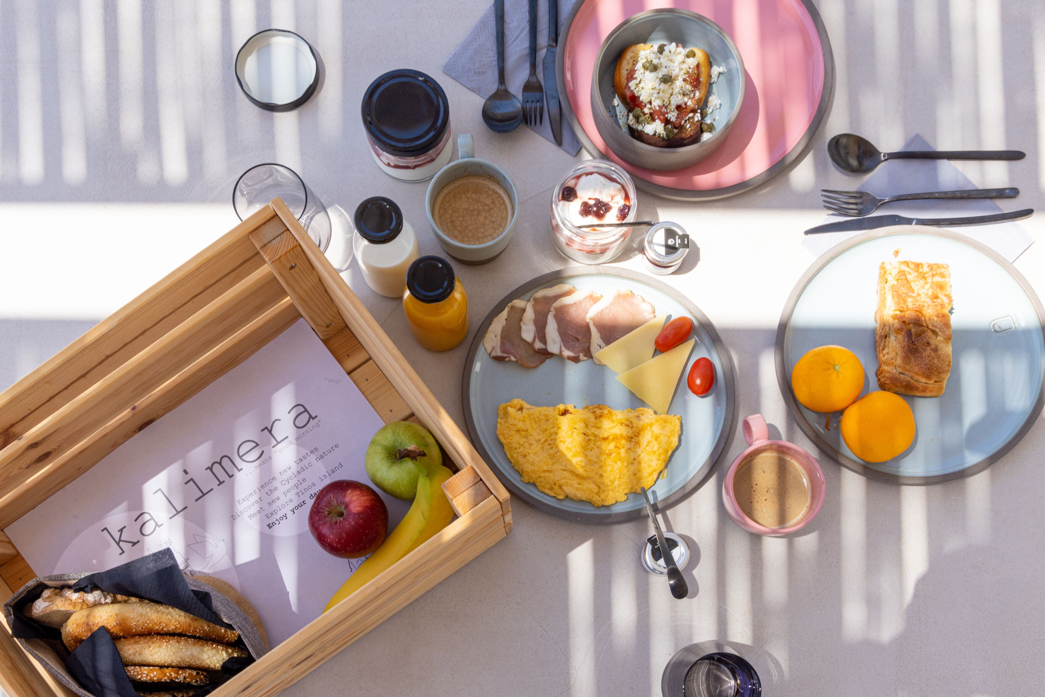 A breakfast setting with a variety of food items, including eggs, fruits, and pastries, arranged on plates and a tray.