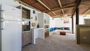 Una cocina moderna con armarios blancos, un refrigerador empotrado y piso de baldosas de piedra.