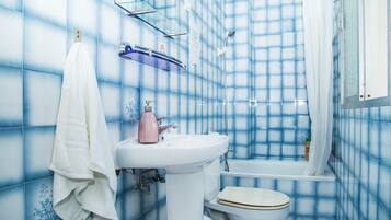 Baño con lavamanos blanco, inodoro y zona de ducha.