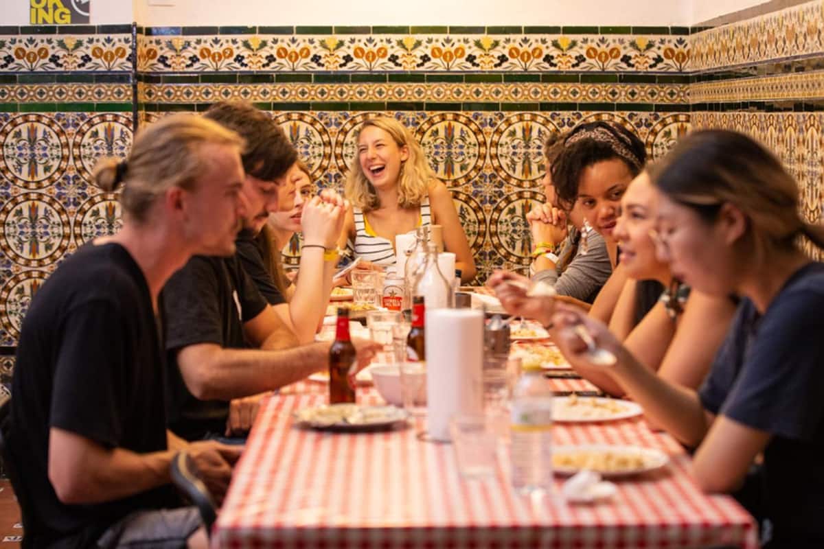 A group of people dining at a restaurant with a tiled wall and a checkered tablecloth.
