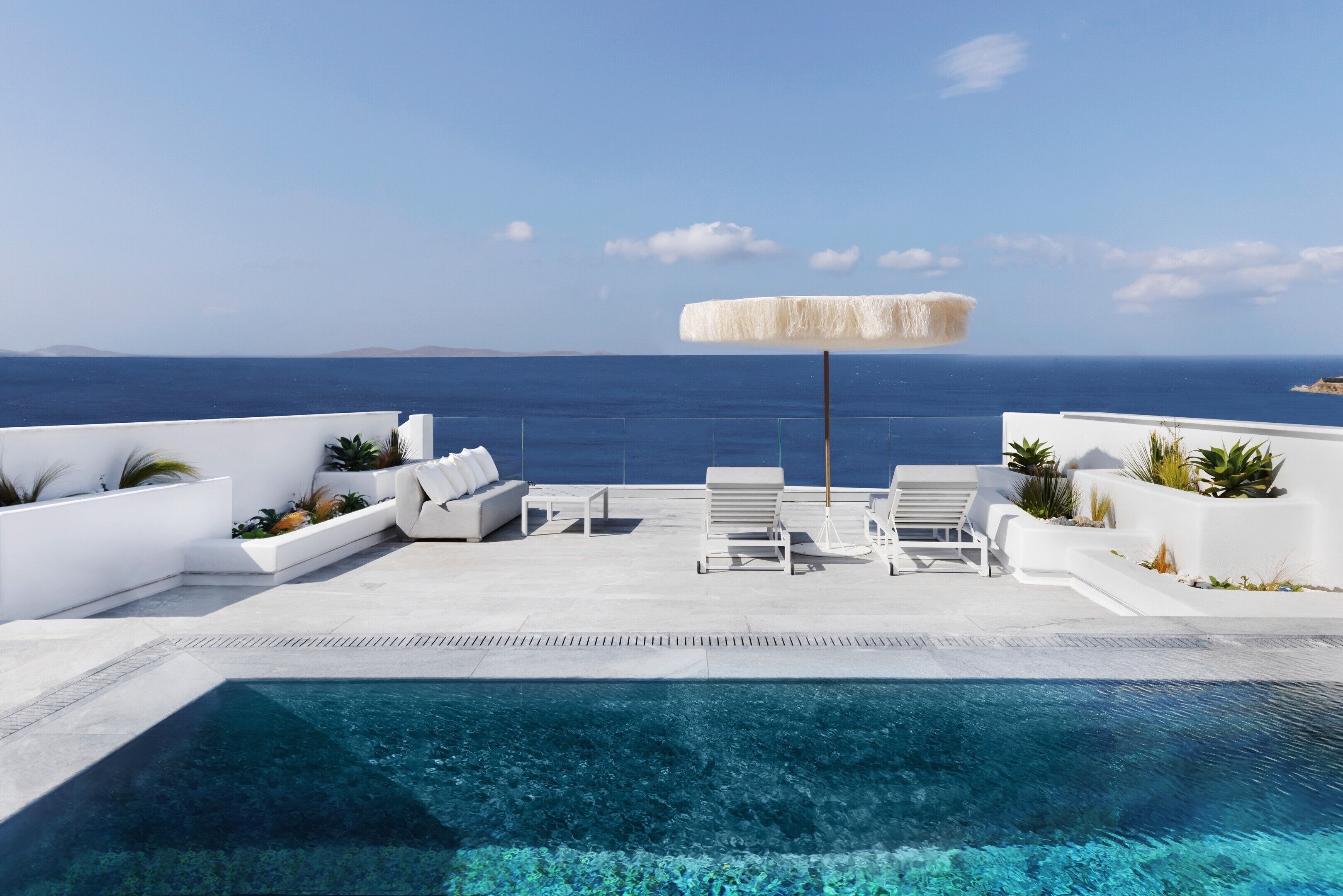 A poolside area with lounge chairs, a small table, and a white umbrella.