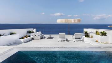 A poolside area with lounge chairs, a small table, and a white umbrella.