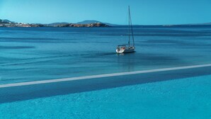 A clear blue pool with a sailboat in the water and a distant shoreline. - Mykonos Riviera Hotel & Spa a member of Small Luxury Hotels of the World (Mykonos)