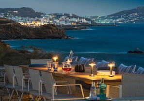 Un área de comedor frente al mar, con una mesa para dos, con vistas a un pueblo costero.