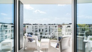 En balkong med vita möbler i rotting och fri utsikt över de omgivande byggnaderna.