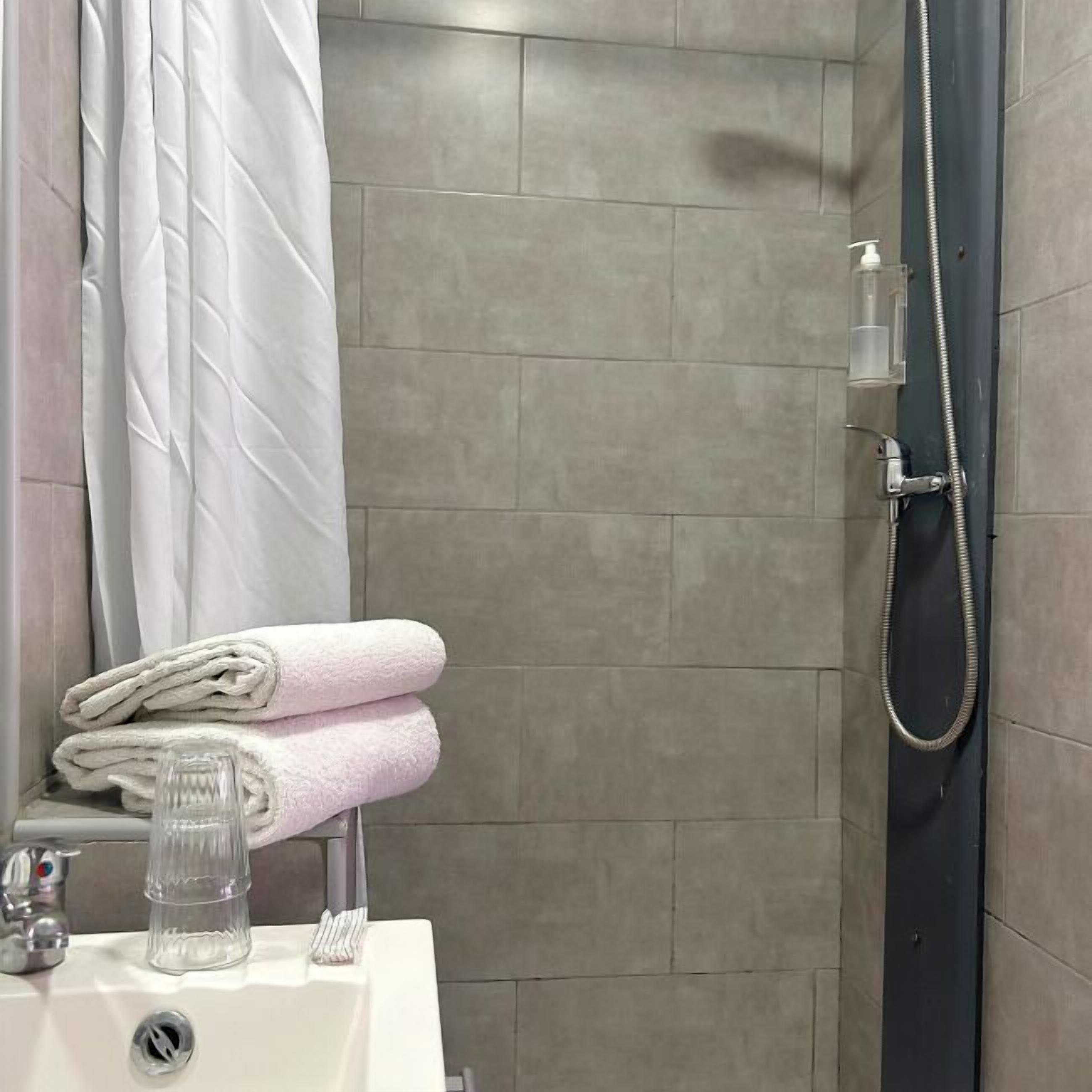 A modern bathroom with a shower, a sink, and a towel rack.