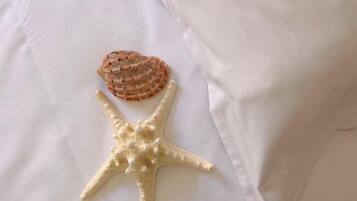 A bed with white sheets and two decorative shells.