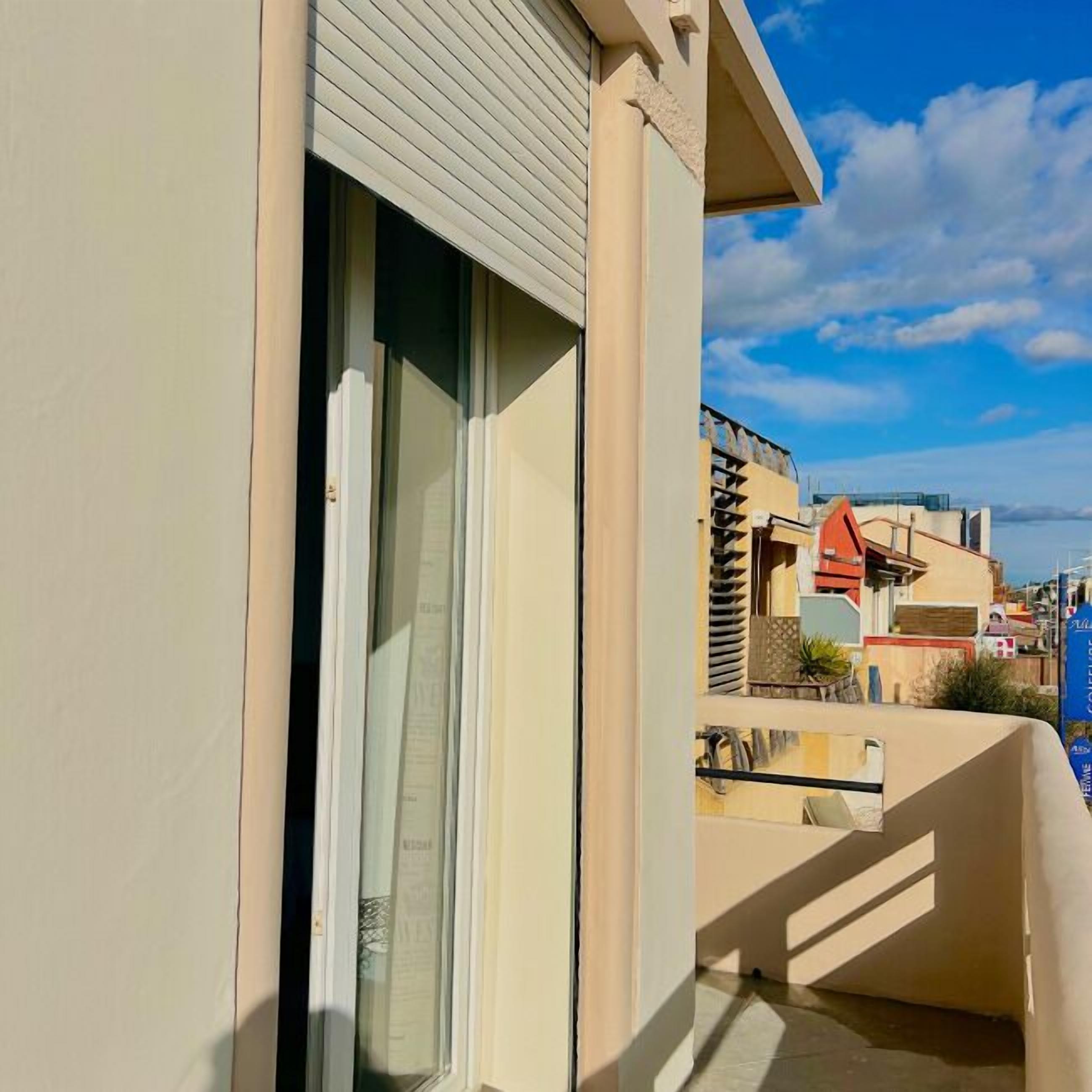 A balcony with a sliding glass door, a view of the sea, and a clear sky.