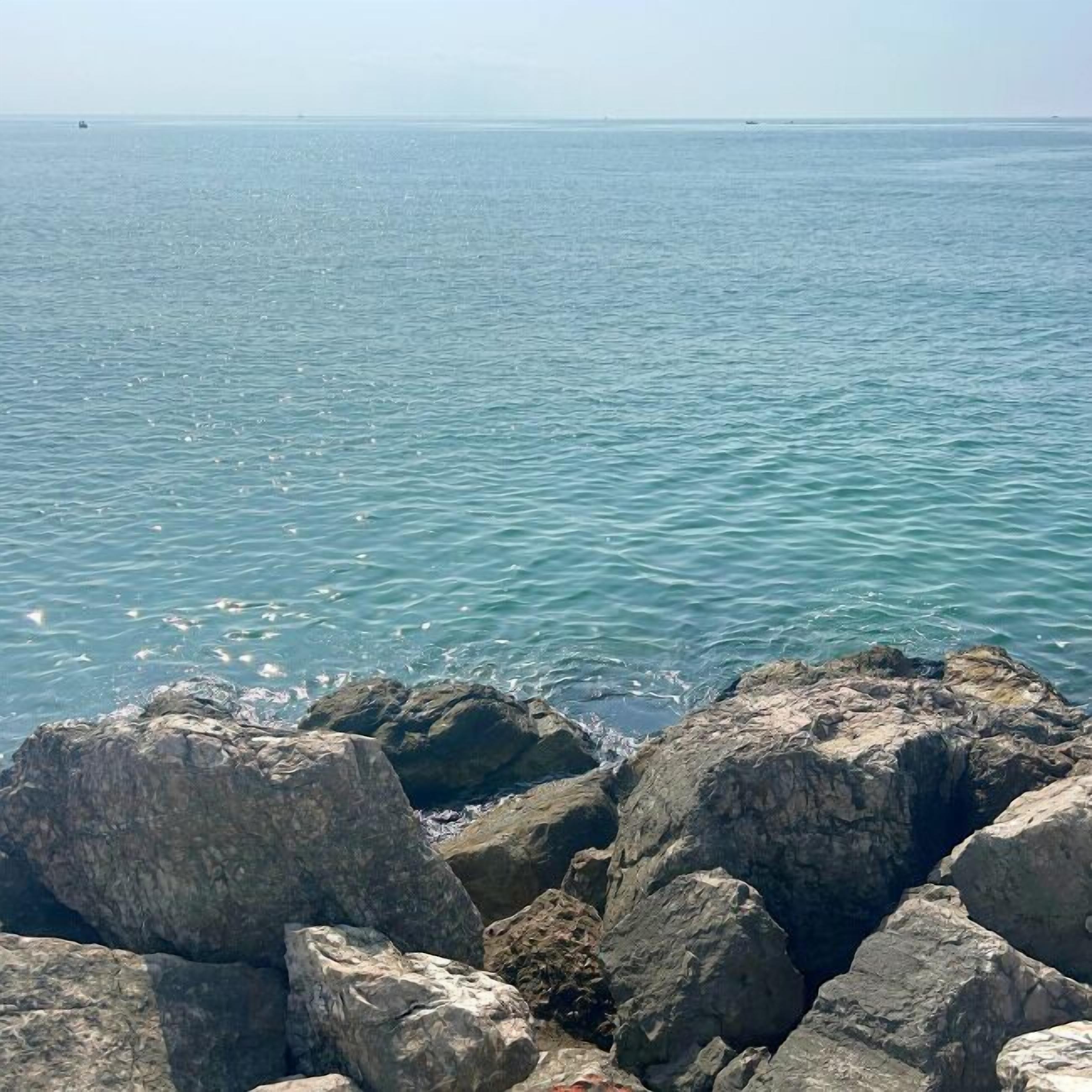 Un rivage rocheux bordé d’une eau d’un bleu limpide.