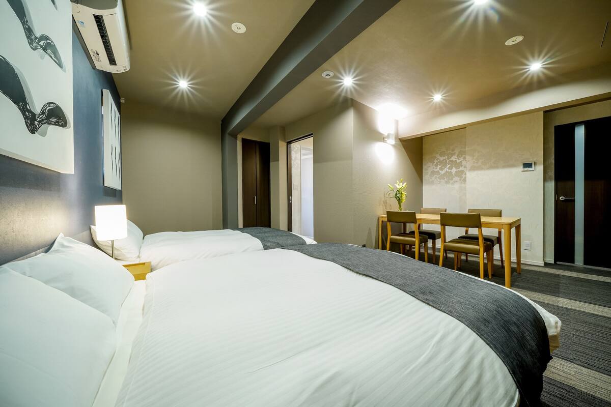 A hotel room with two beds, a desk, and a chair.