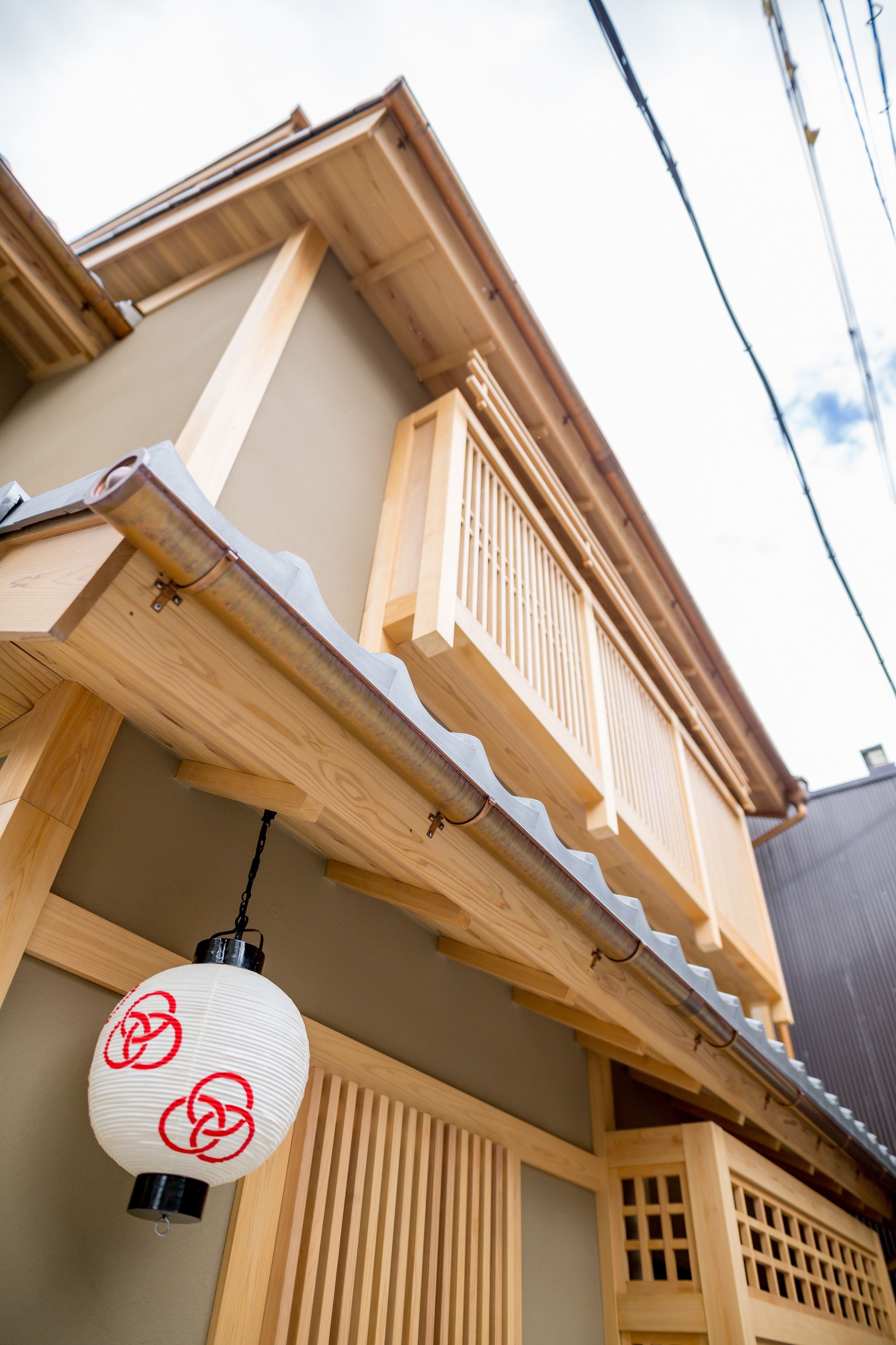 A traditional Japanese house with a wooden balcony and a hanging lantern.