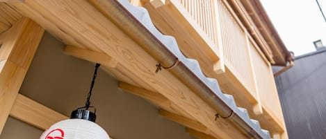 Une maison traditionnelle japonaise dotée d’un balcon en bois et d’une lanterne suspendue.