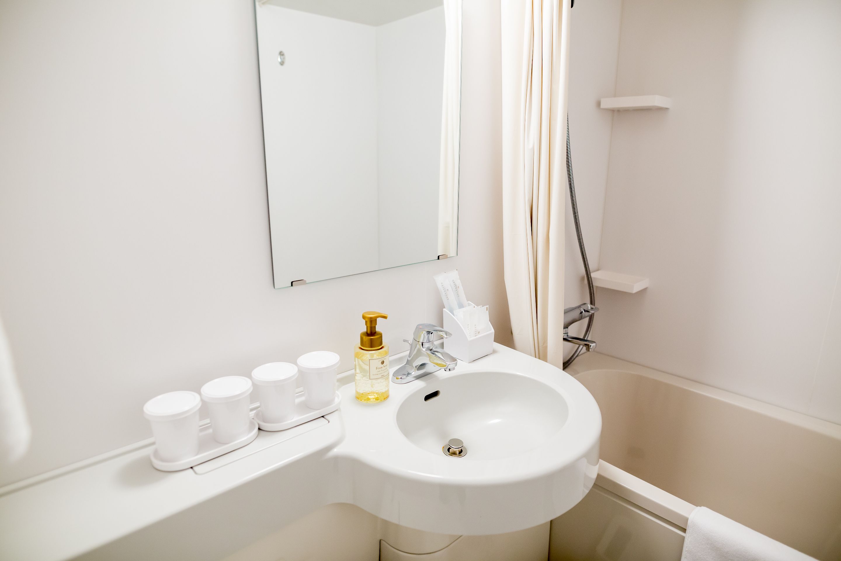 Une salle de bain avec un lavabo blanc, un miroir et une douche.