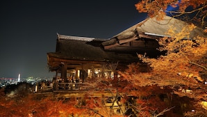 A traditional Japanese building with a wooden structure and a thatched roof, surrounded by autumn foliage. - RESI STAY Tsubaki (Kyoto)