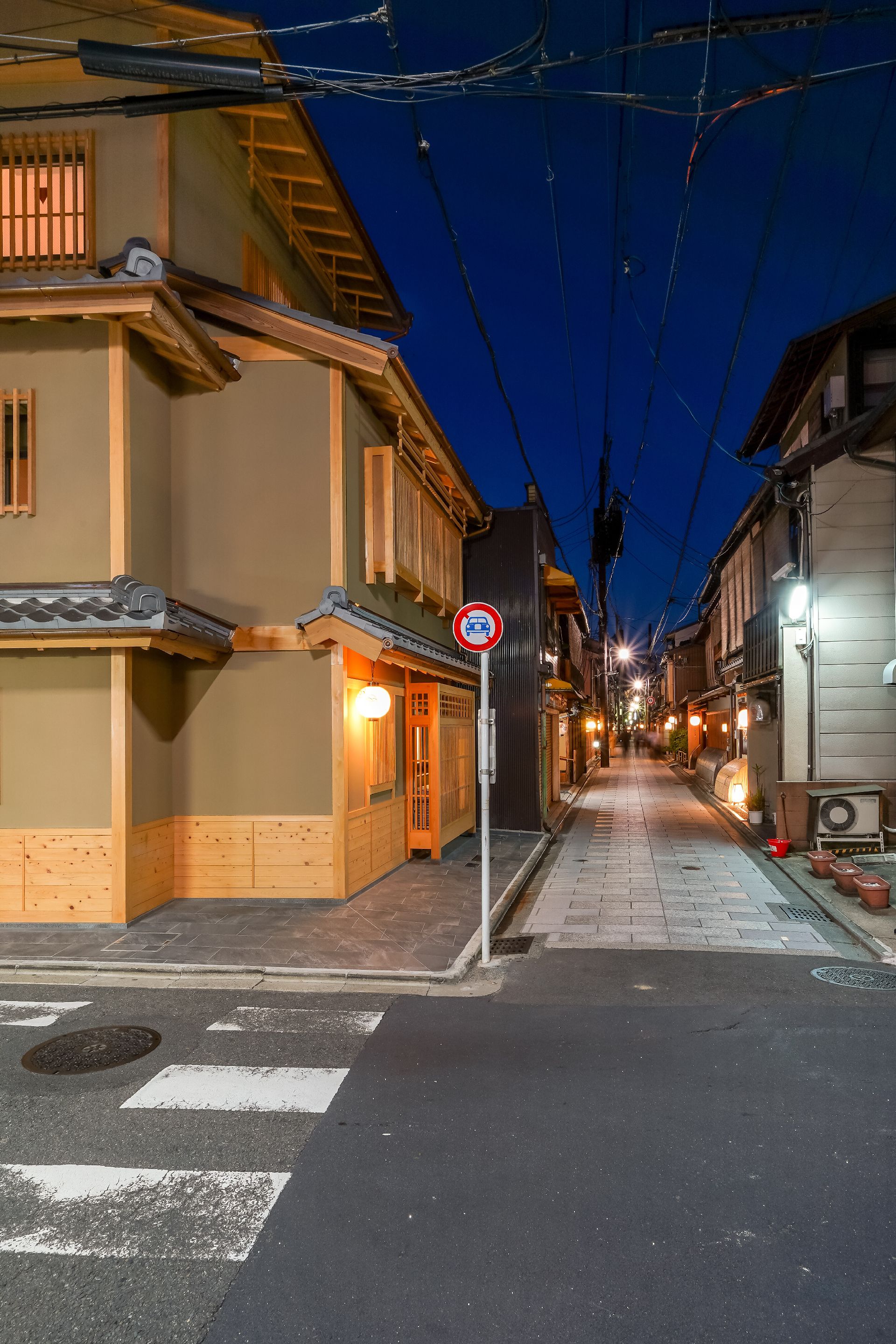 A narrow street lined with traditional buildings, a no parking sign, and a pedestrian crossing.