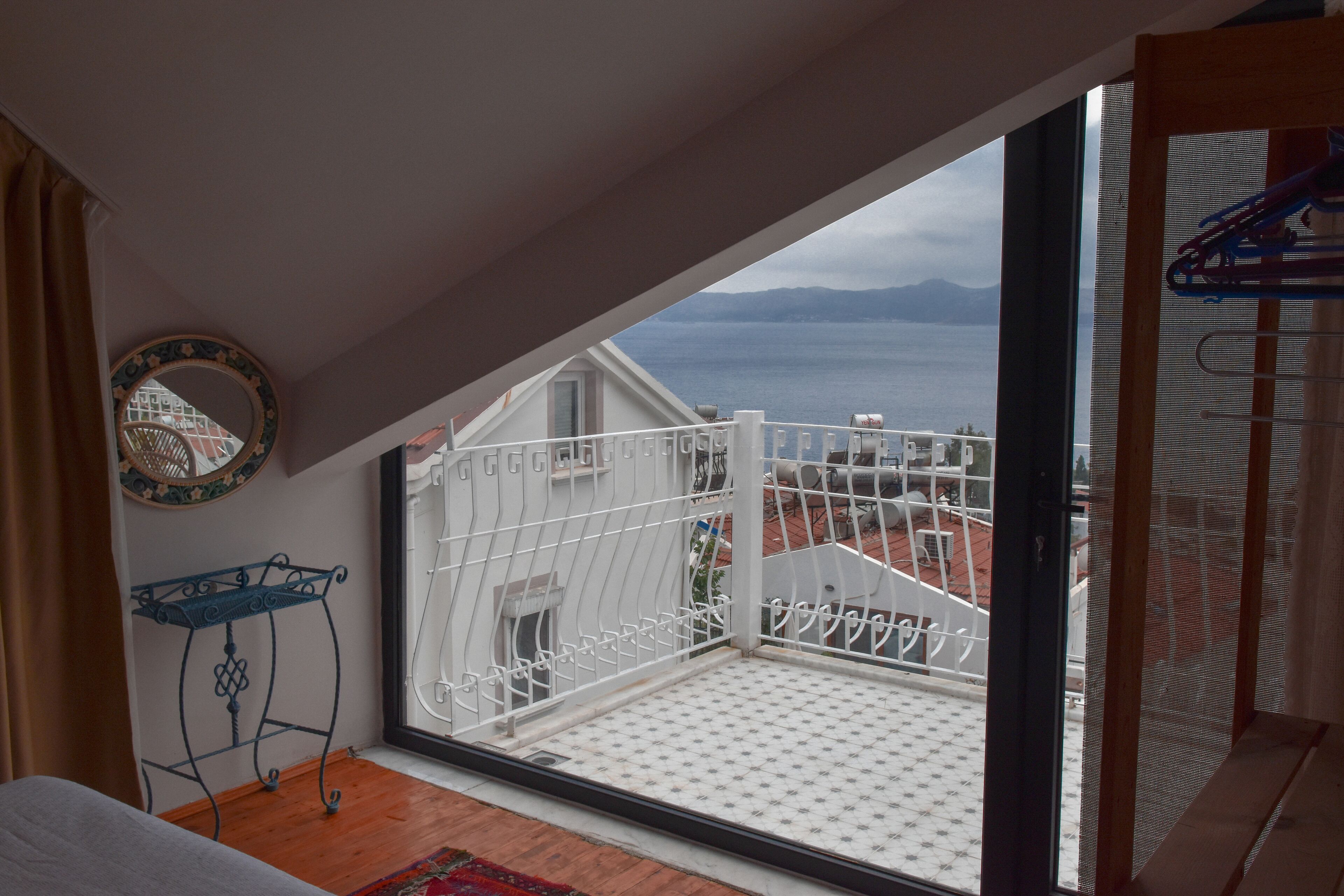En balkon med udsigt over havet, et hvidt gelænder og et lille bord med et spejl.