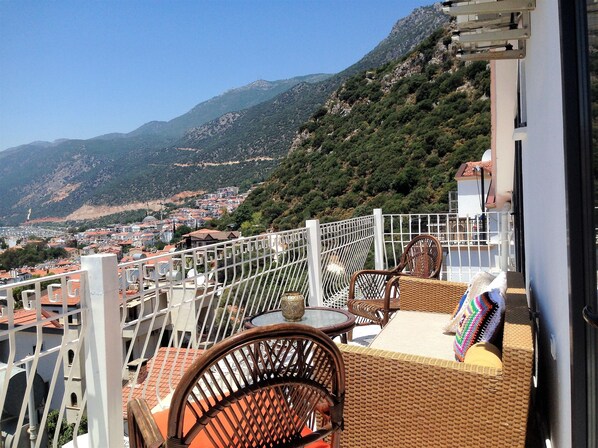 A balcony with wicker furniture, a view of a town and mountains. - Smyrna Pansiyon (Kas)