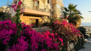 A multi-story building with balconies, surrounded by vibrant pink bougainvillea flowers. - Smyrna Pansiyon (Kas)