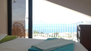 A hotel room with a bed, a view of the sea, and a balcony with a railing. - Smyrna Pansiyon (Kas)