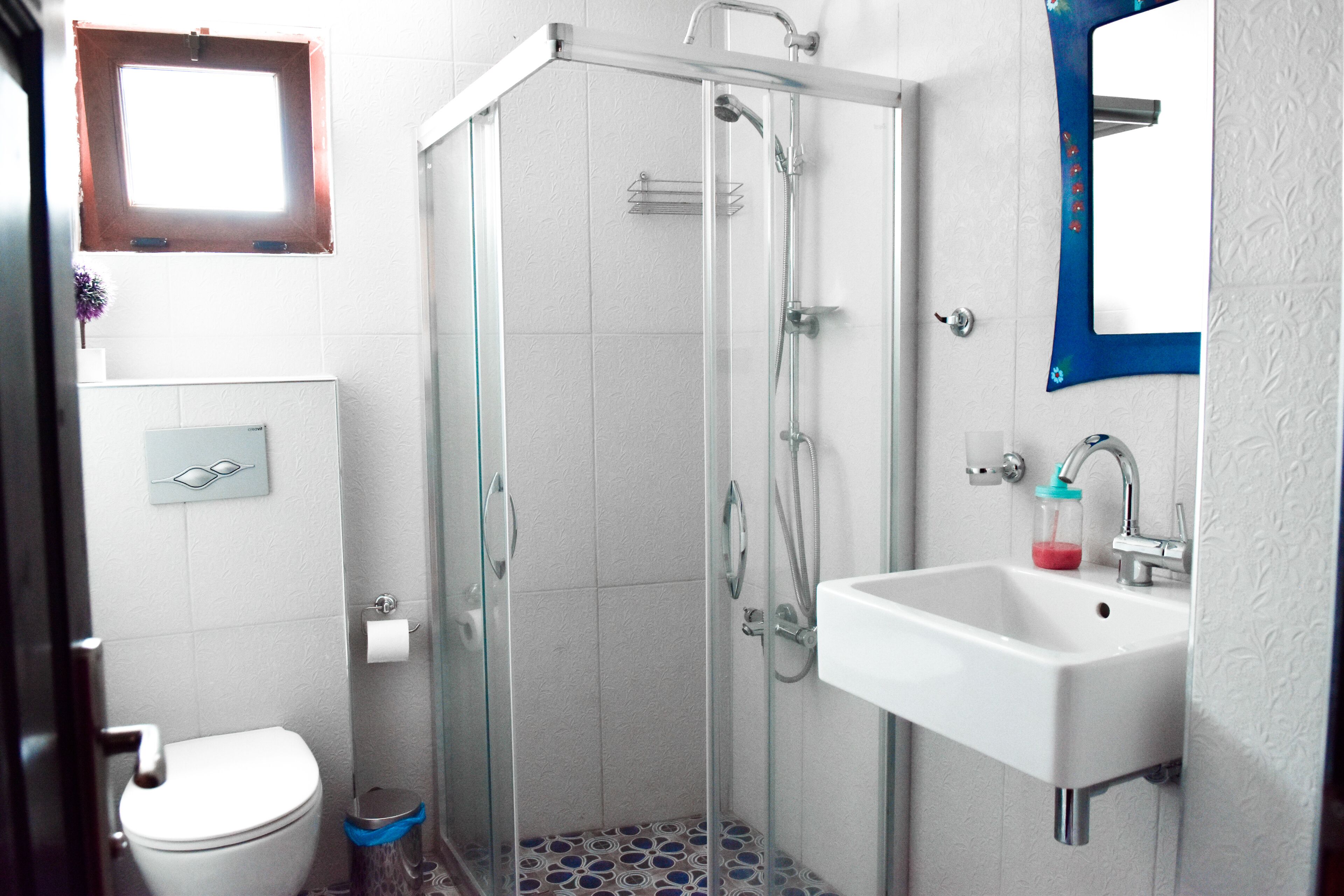 A bathroom with a glass-enclosed shower, a white sink, and a toilet.