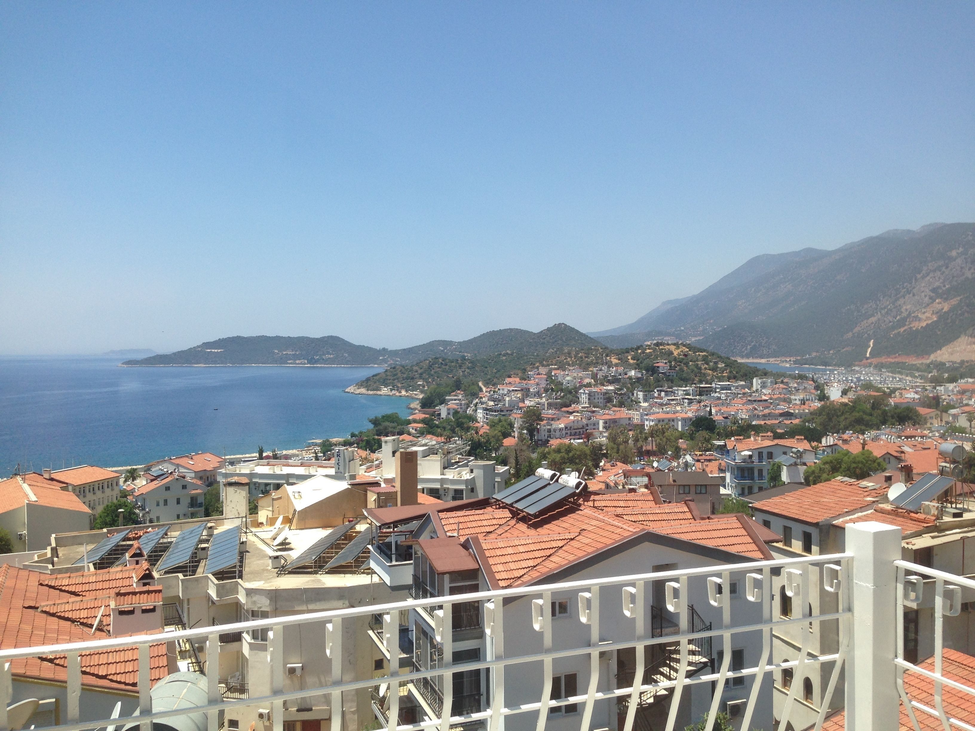 A coastal cityscape with buildings, a clear sky, and a view of the sea.