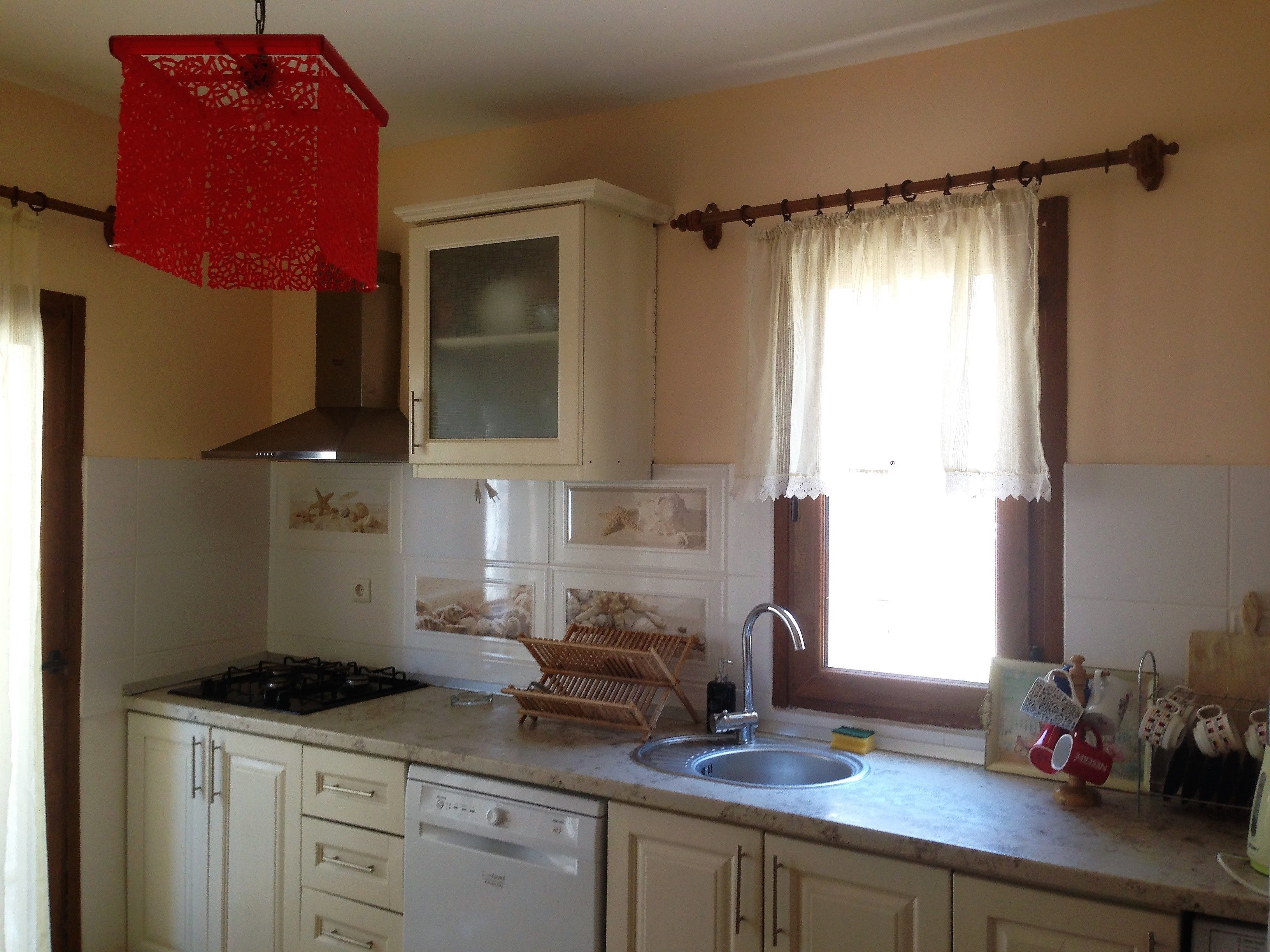 A kitchen with a stove, sink, and cabinets.
