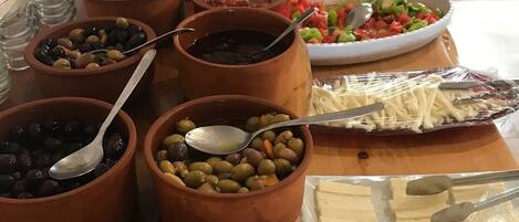 A buffet table with various dishes including olives, beans, and cheese.