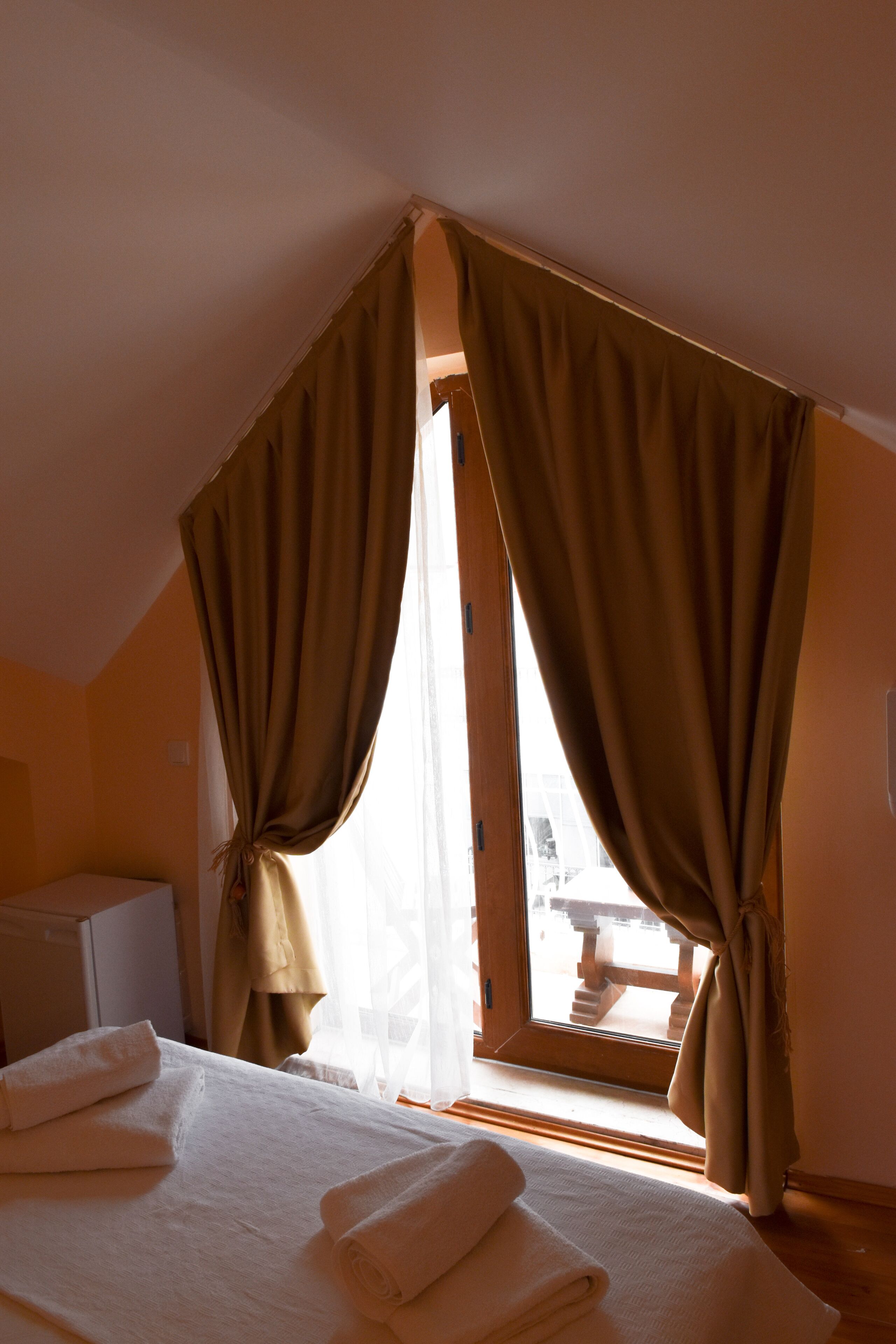 Une chambre à coucher avec un lit, une fenêtre avec des rideaux et une vue sur un espace extérieur.