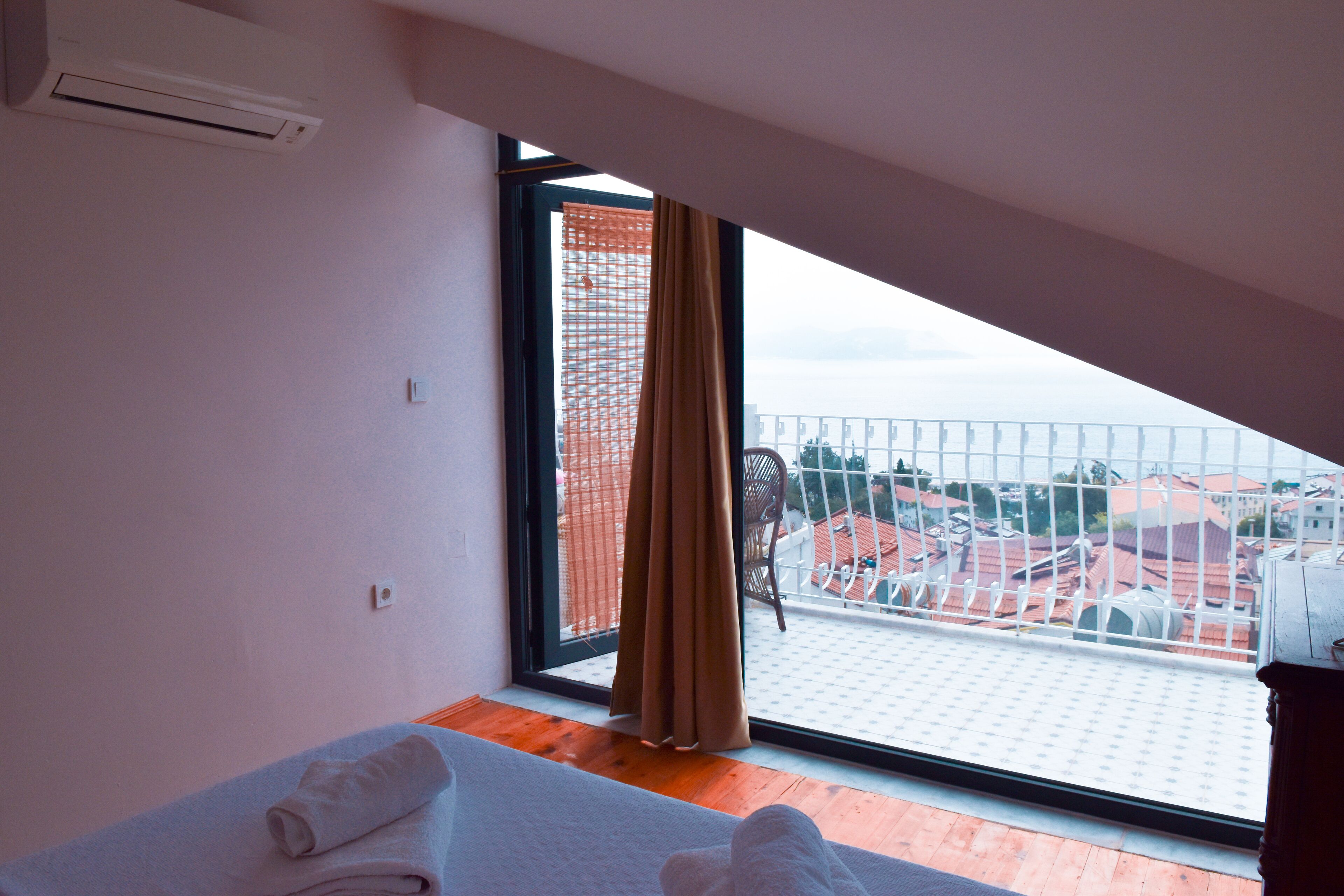A hotel room with a large window, a bed with towels, and a view of buildings outside.