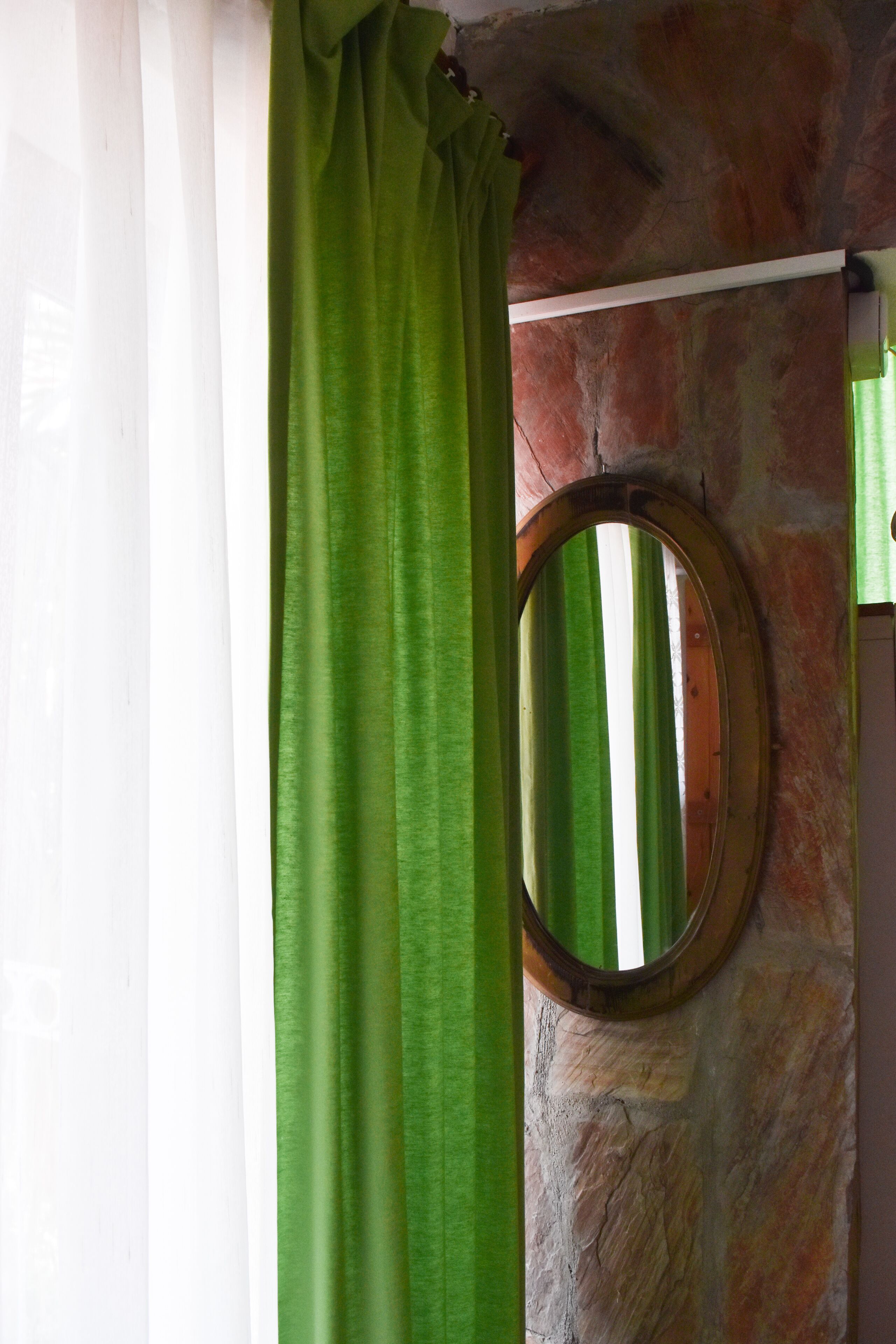 A room with a stone wall, a wooden door, and a green curtain.