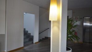 A modern kitchen with a stainless steel refrigerator, a potted plant, and a staircase leading to another level. - Hotel Cavalieri Pinerolo (Pinerolo)