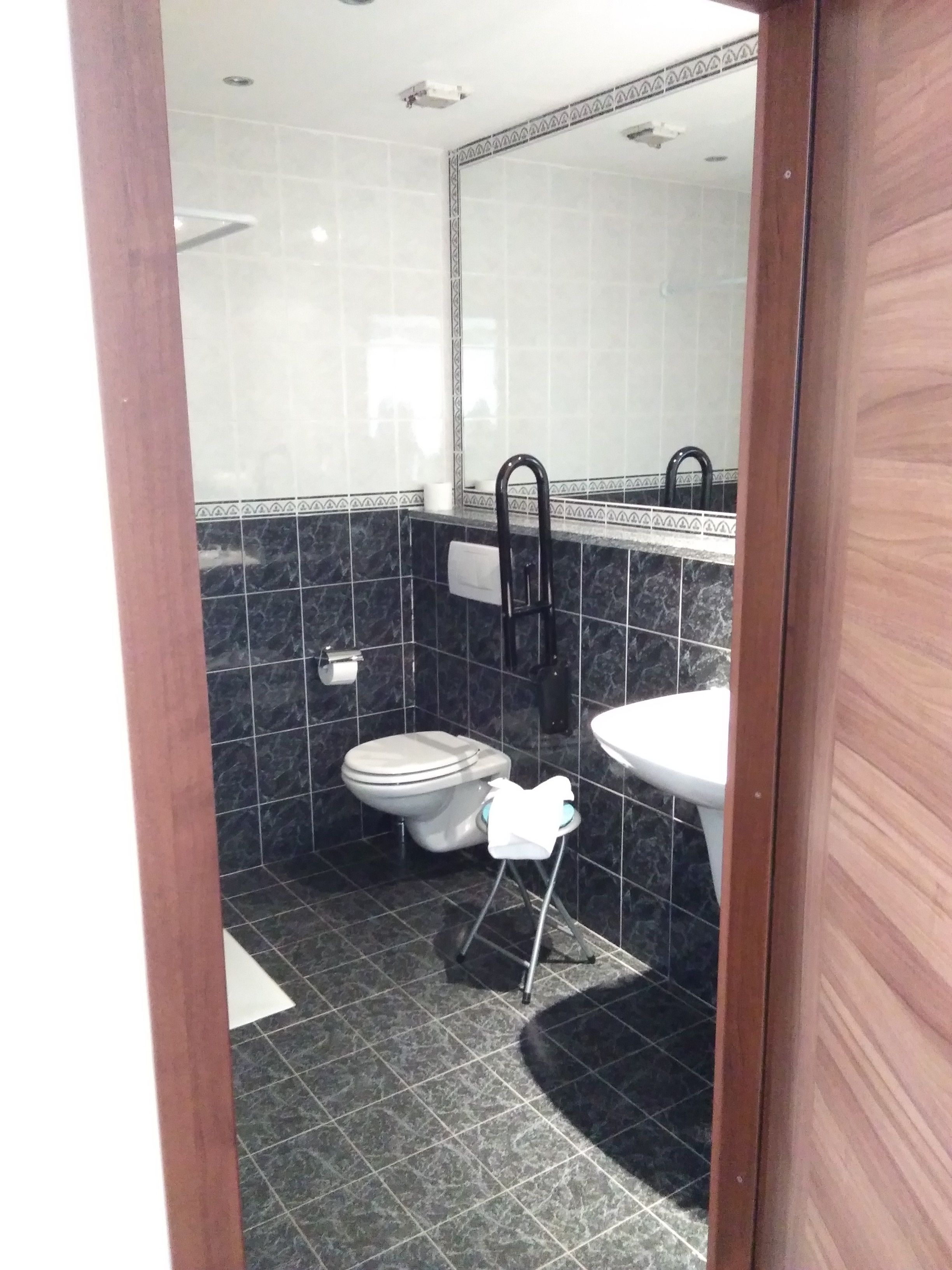 A small bathroom with a toilet, sink, and mirror.