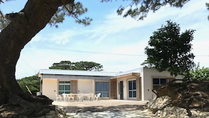 A modern building with a patio area featuring outdoor seating. - Pension Ishigaki Tomatamatsu (Ishigaki)